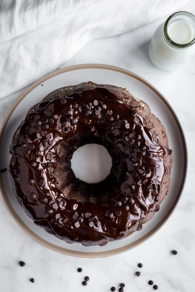 Top down shot of chocolate glazed chocolate cake with milk in the background
