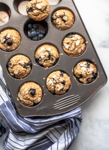 Muffin tray full of healthy blueberry muffins on a blue kitchen towel