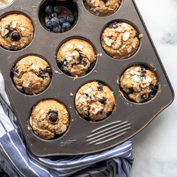 Muffin tray full of healthy blueberry muffins on a blue kitchen towel
