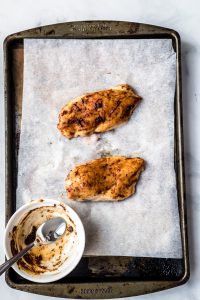 Baked chicken breasts for two on a parchment paper lined baking sheet