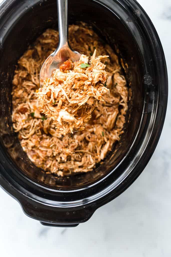 Slow cooker shredded Mexican chicken being scooped out of slow cooker