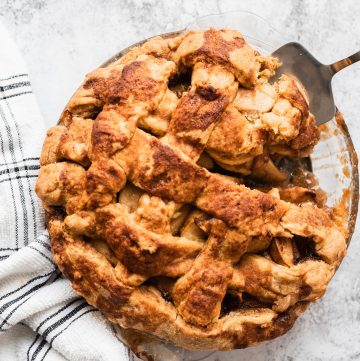 Easy apple pie in a glass pie plate with a slice being lifted out