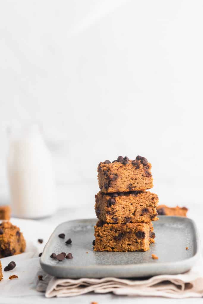 healthy pumpkin bars stacked with a glass of milk at the back