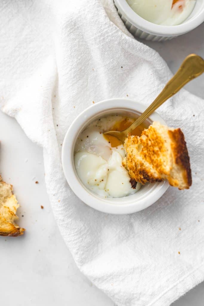 Sous vide egg in ramekin with runny yolk and a piece of bread
