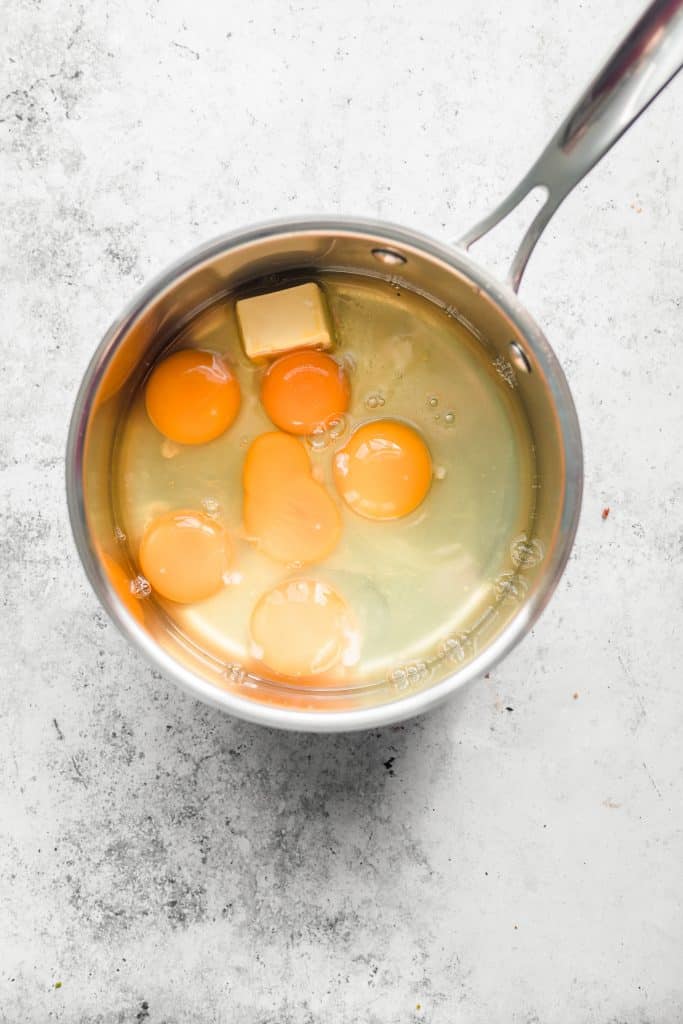 Raw eggs in saucepan with knob of butter