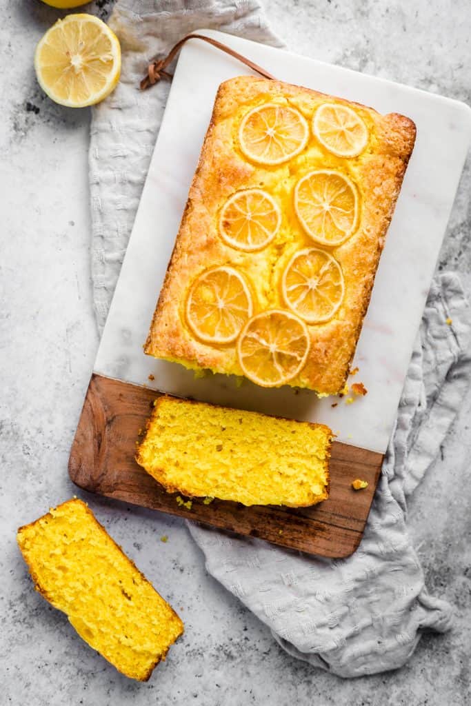 Lemon turmeric cake sliced on a chopping board with a kitchen towel