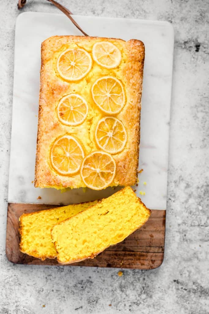 Lemon turmeric cake sliced on a chopping board with a kitchen towel