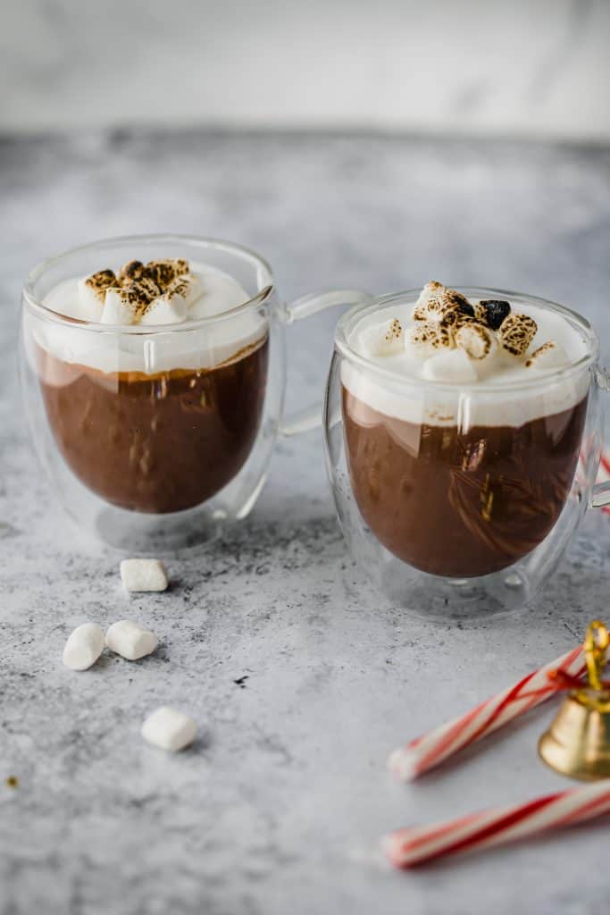 Hot chocolate photography in two clear mugs with whipped cream and marshmallows