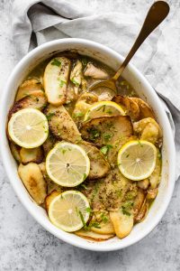 Baking dish with Lebanese chicken and potatoes with a spoon scooping some out
