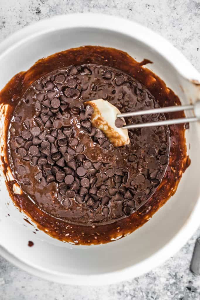 Brownie batter being mixed in a bowl with chocolate chips
