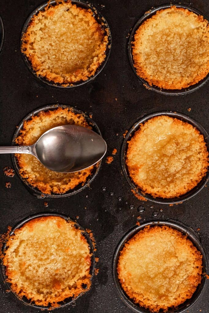 baked kunafa cups out of the oven with syrup being poured on top