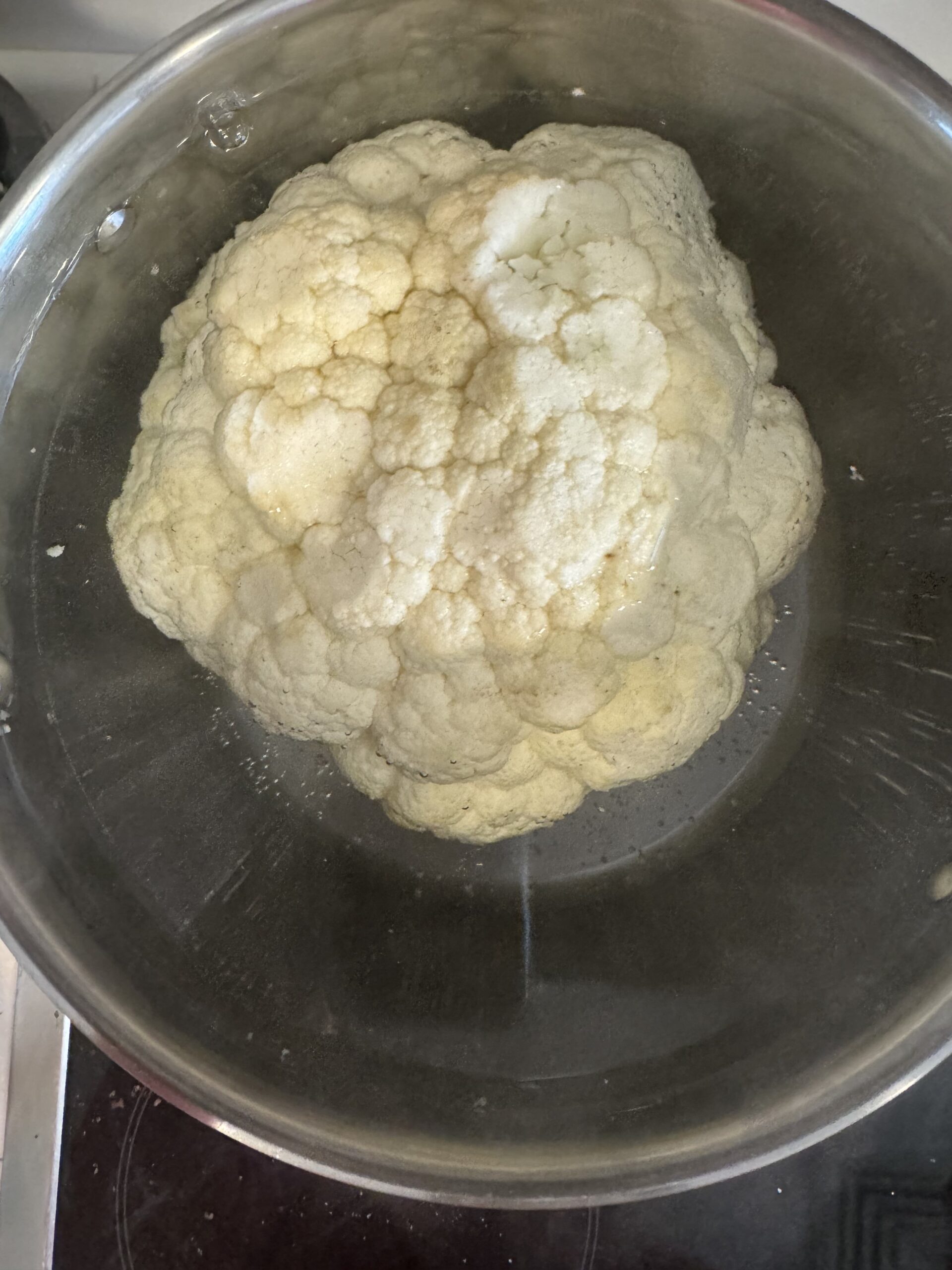 whole cauliflower boiling in a big pot of water
