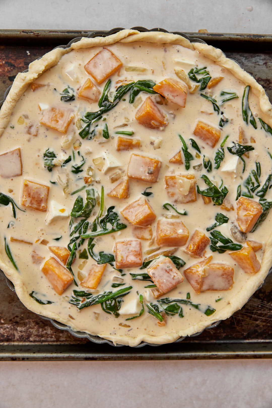 quiche batter in the unbaked puff pastry crust on a baking sheet.