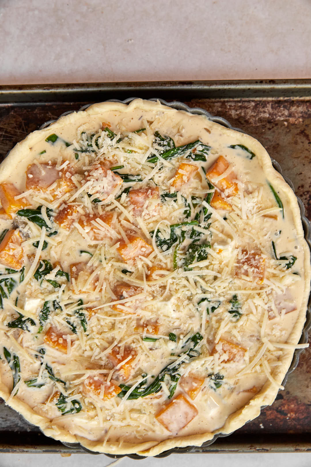 parmesan cheese topped quiche before going in oven on a baking sheet.