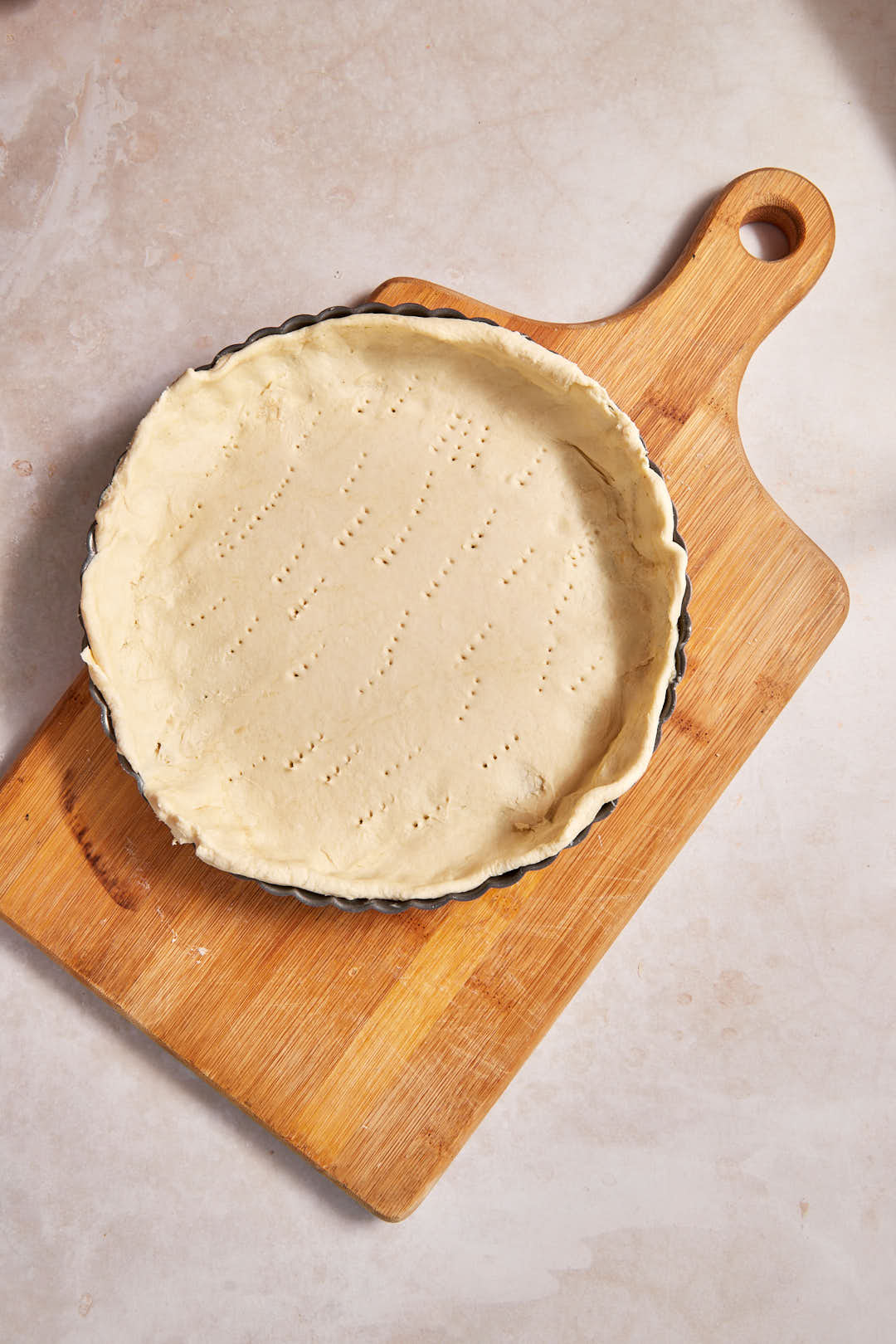 tart pan filled with puff pastry on a wooden board.