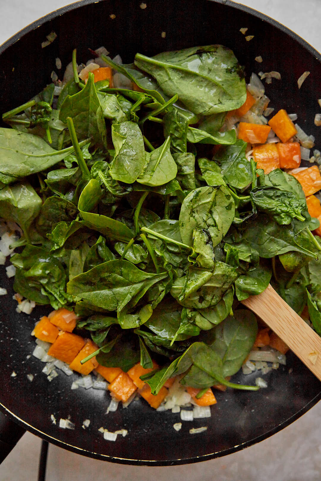 baby spinach added to pumpkin cubes in a large skillet.