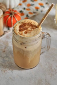 pumpkin cold foam coffee with small fake pumpkins in the background on a white background,.