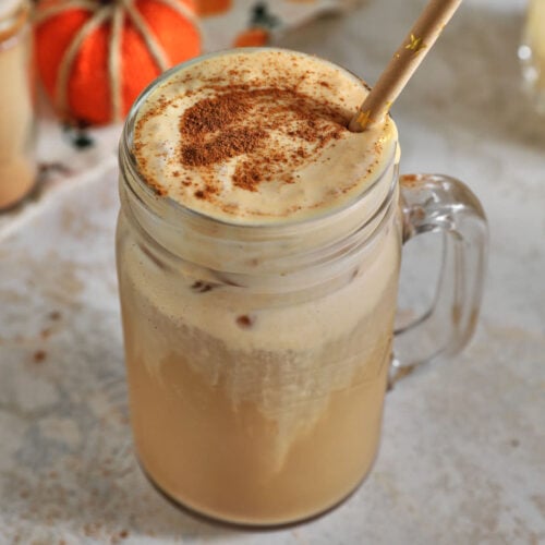 pumpkin cold foam coffee with small fake pumpkins in the background on a white background,.
