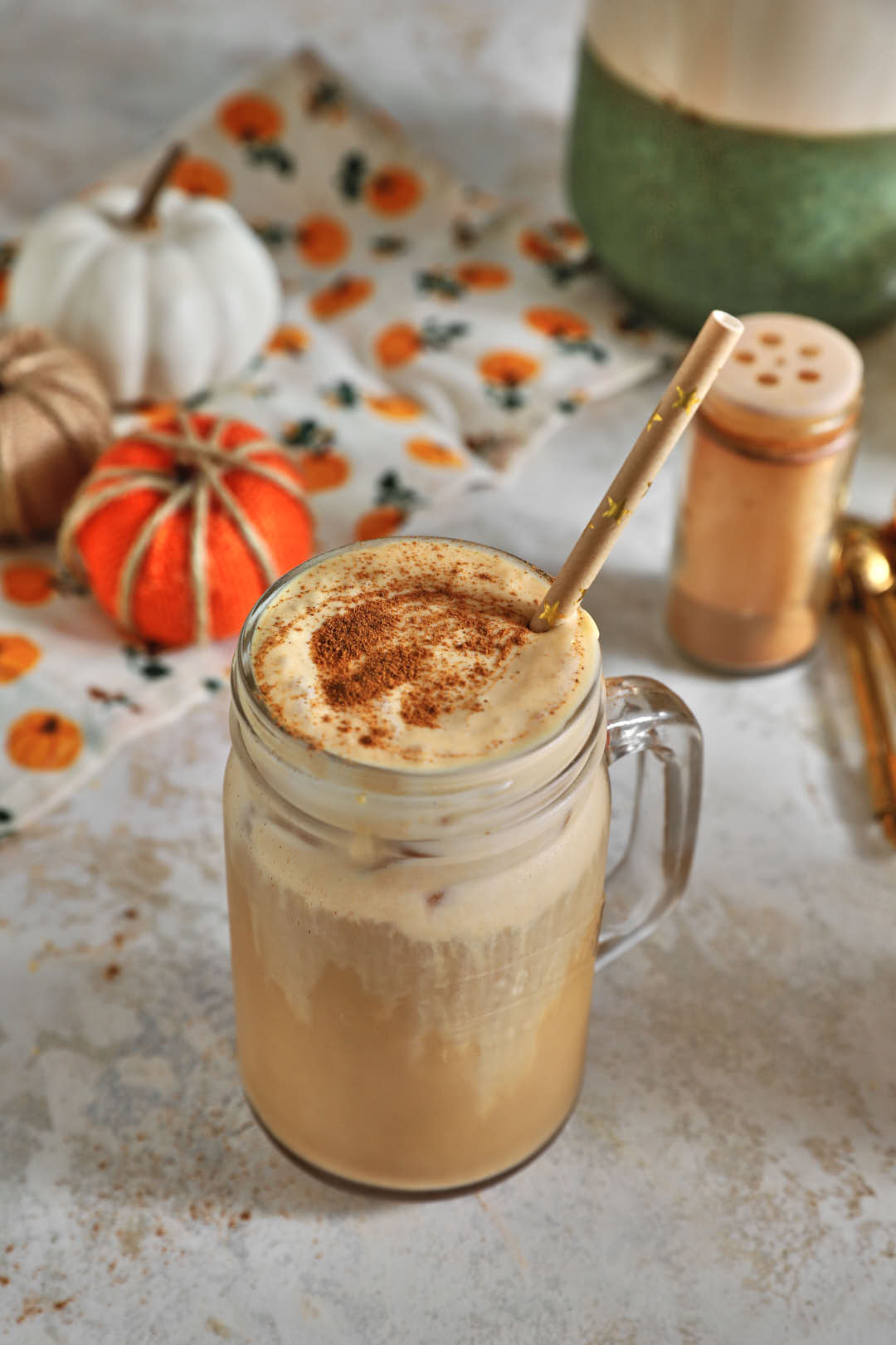 pumpkin cold brew coffee in a glass mason jar with a straw and cinnamon in the background.