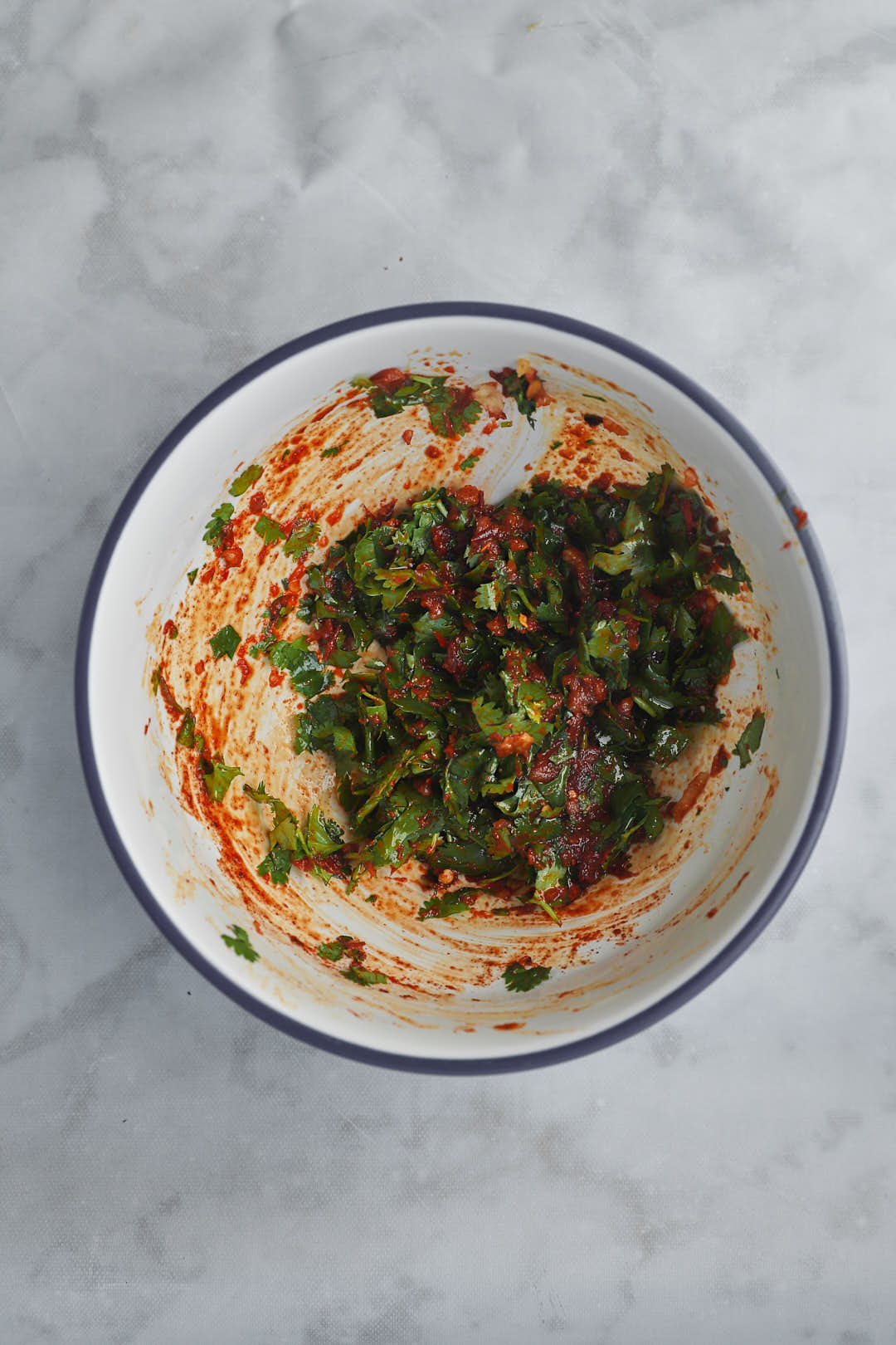 red pepper paste and herbs stirred together in a bowl.