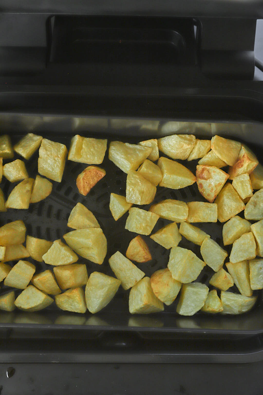 air fryed potato cubes in basket of air fryer.