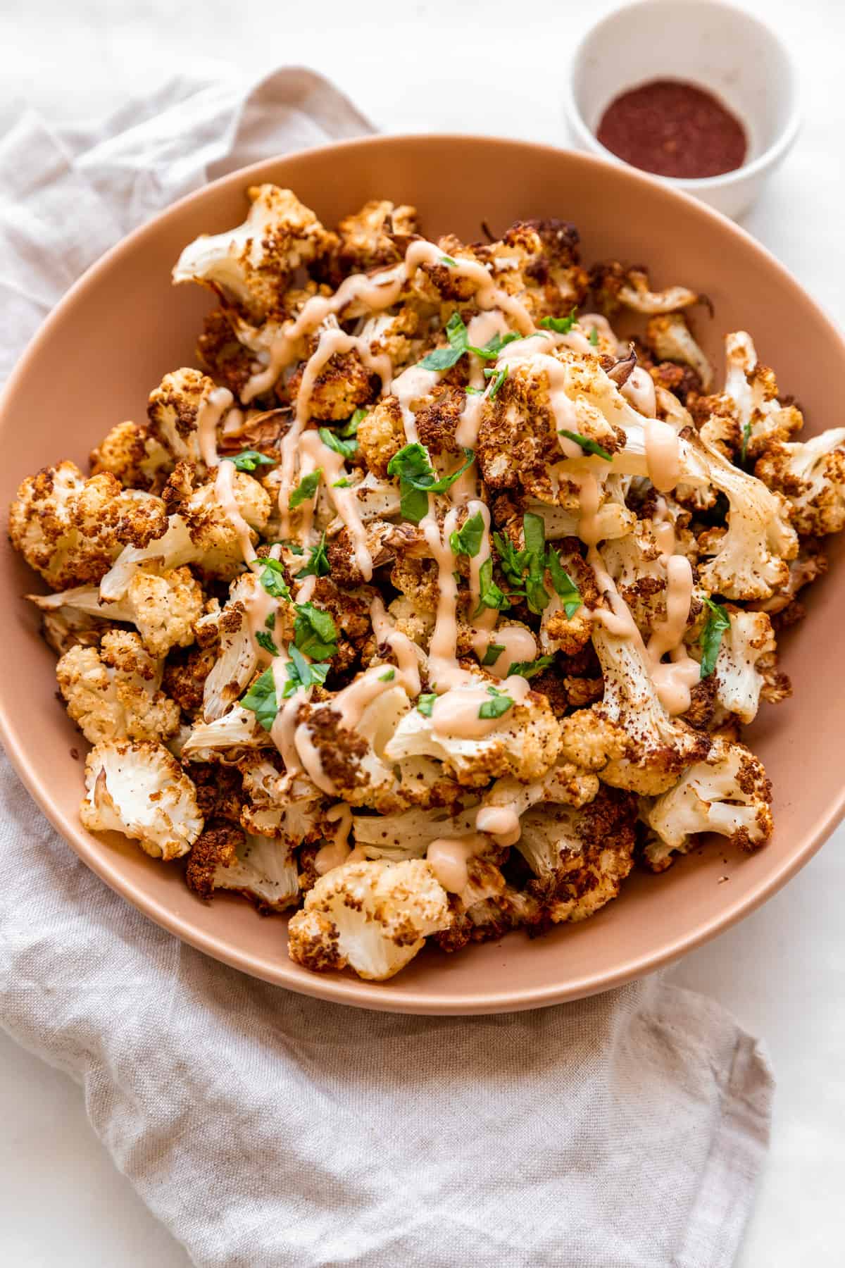 air fryer cauliflower in a beige plate with tahini on top.