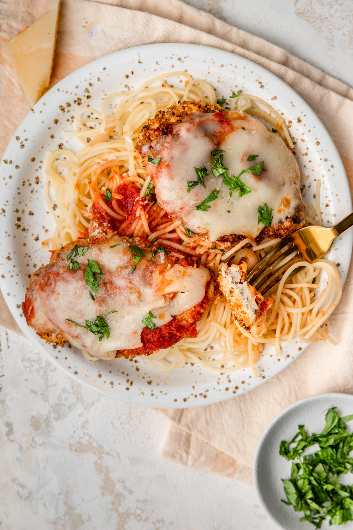 Close up of air fryer chicken parmesan with a fork grabbing some noodles.