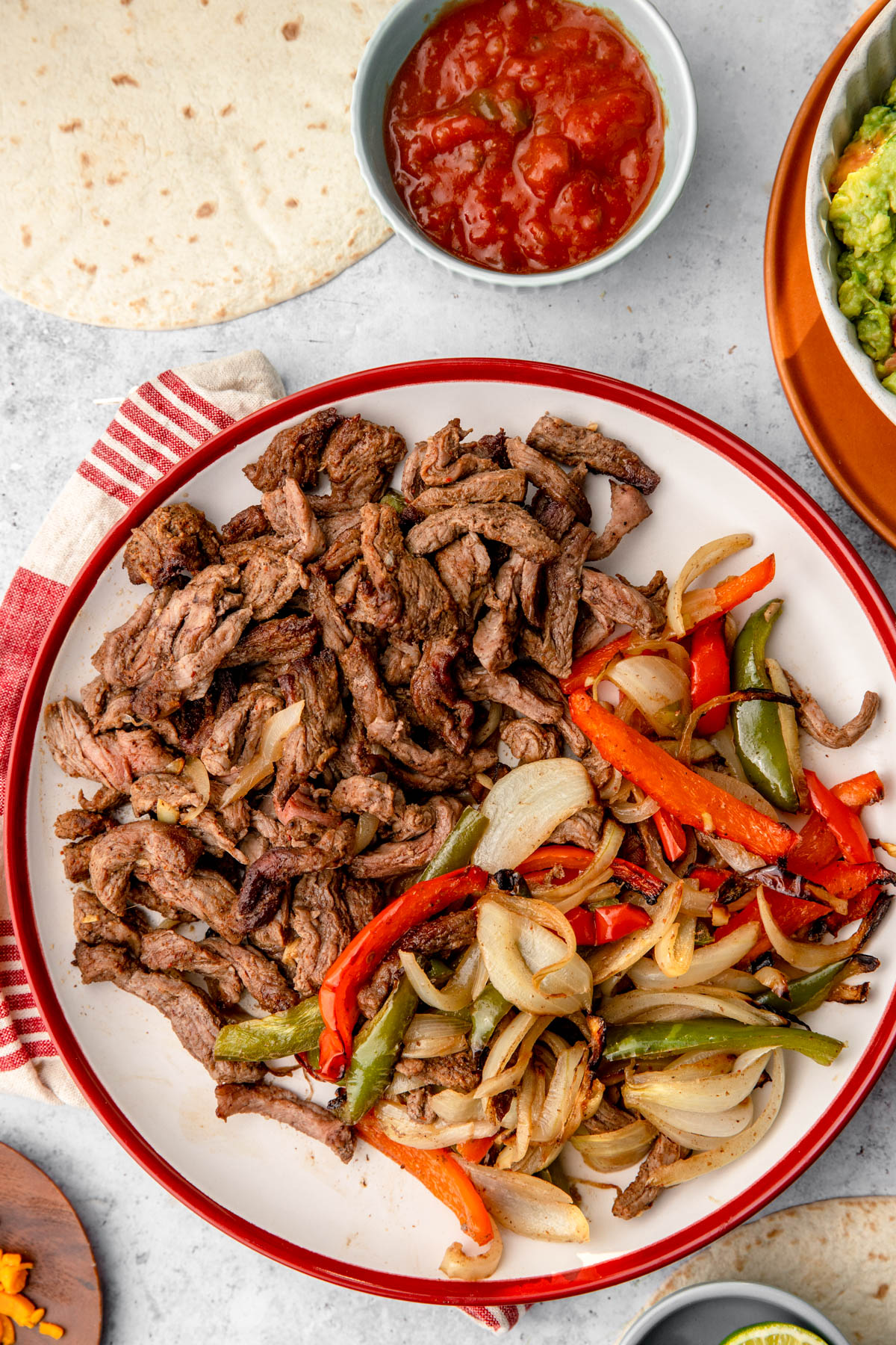 air fryer steak fajitas on a plate with guacamole and sour cream on side