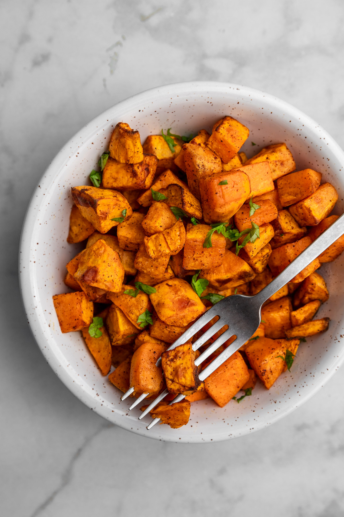 air fryer roasted sweet potato cubes with a fork spearing one.
