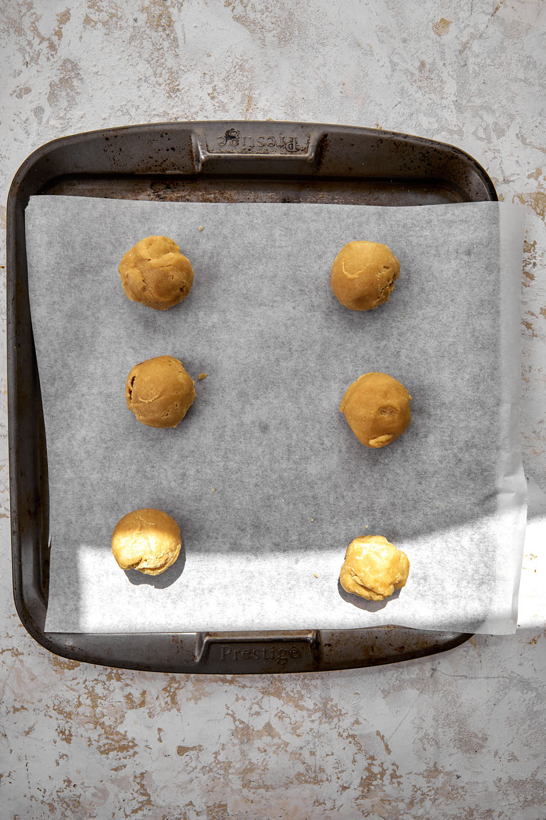 cookie dough balls in parchment paper lined baking sheet.
