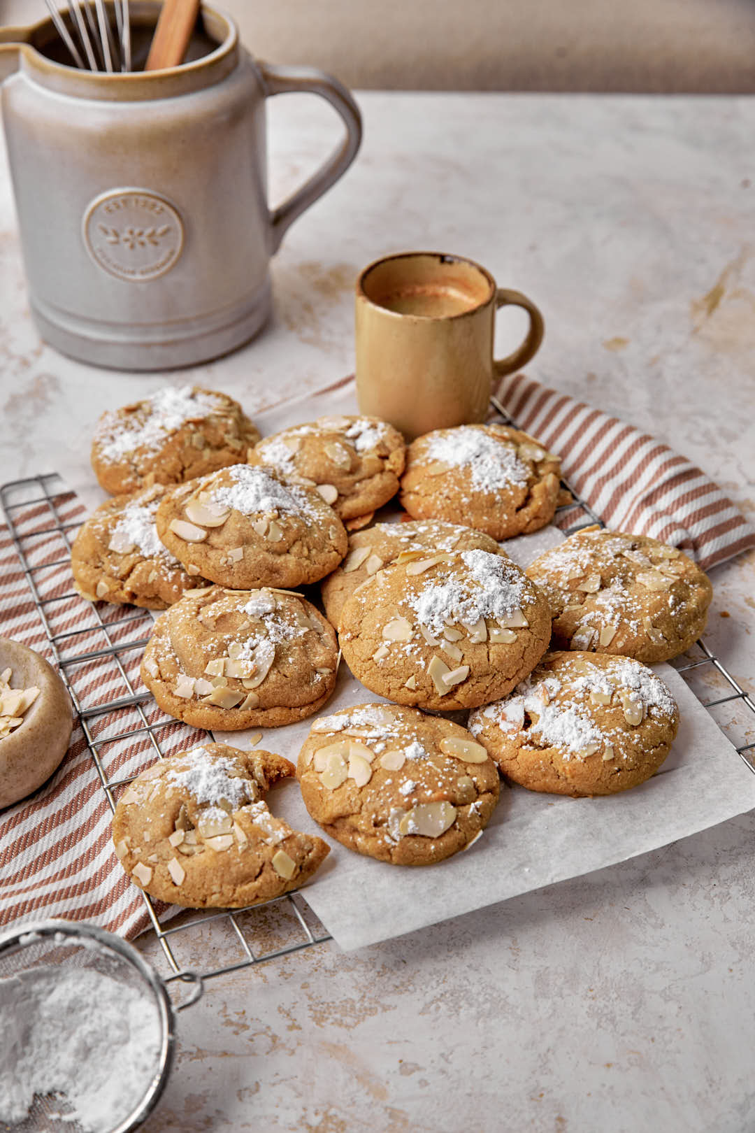 Almond cookies on parchment paper lined baking sheet with an espresso cup in the background.