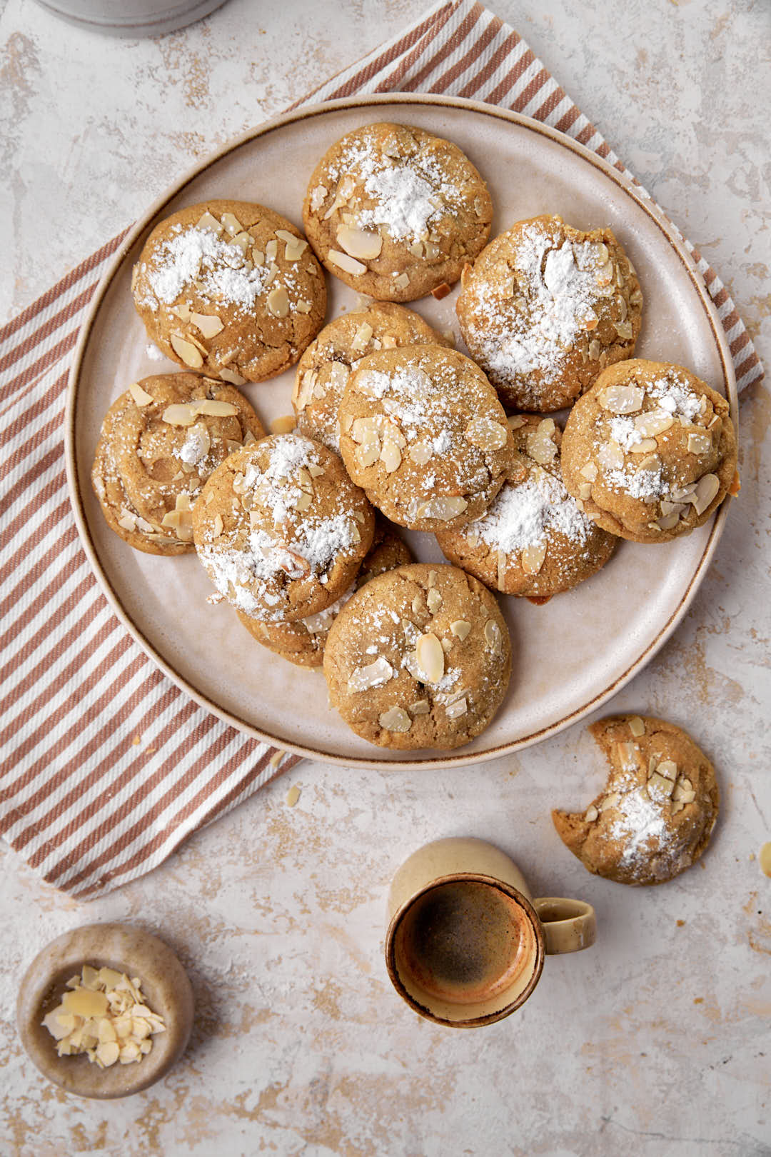 a plate of almond croissant cookies with a cup of coffee on the side.