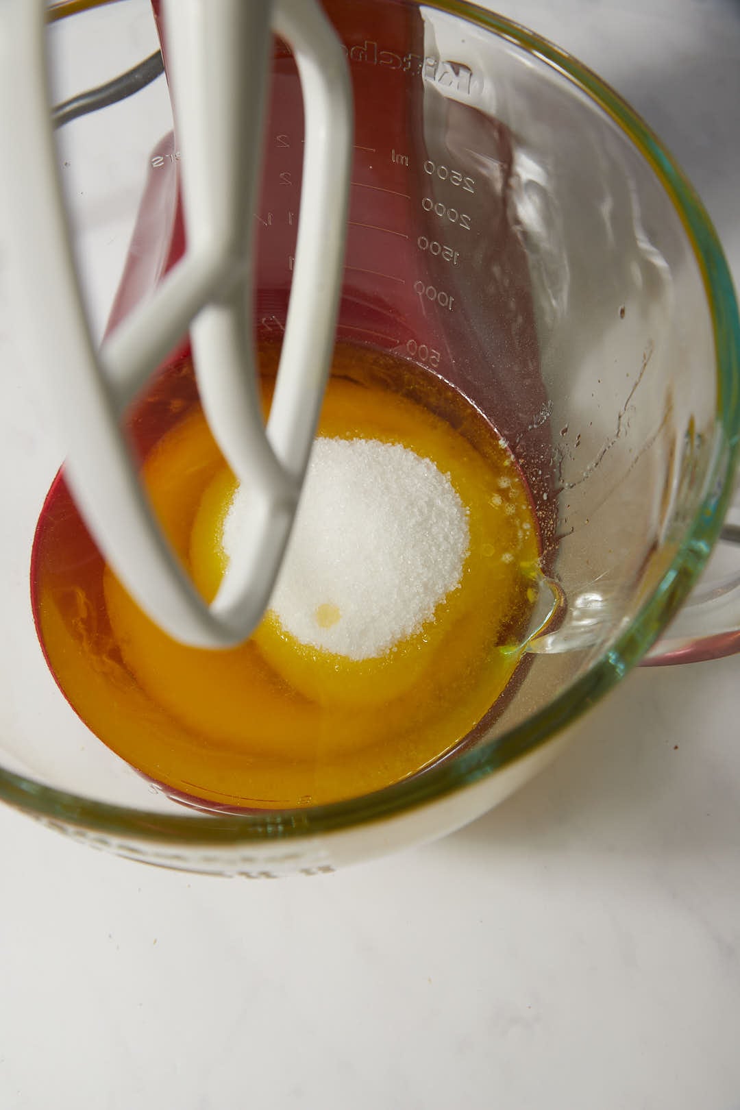 olive oil, melted butter, and sugar in a glass kitchen aid bowl.