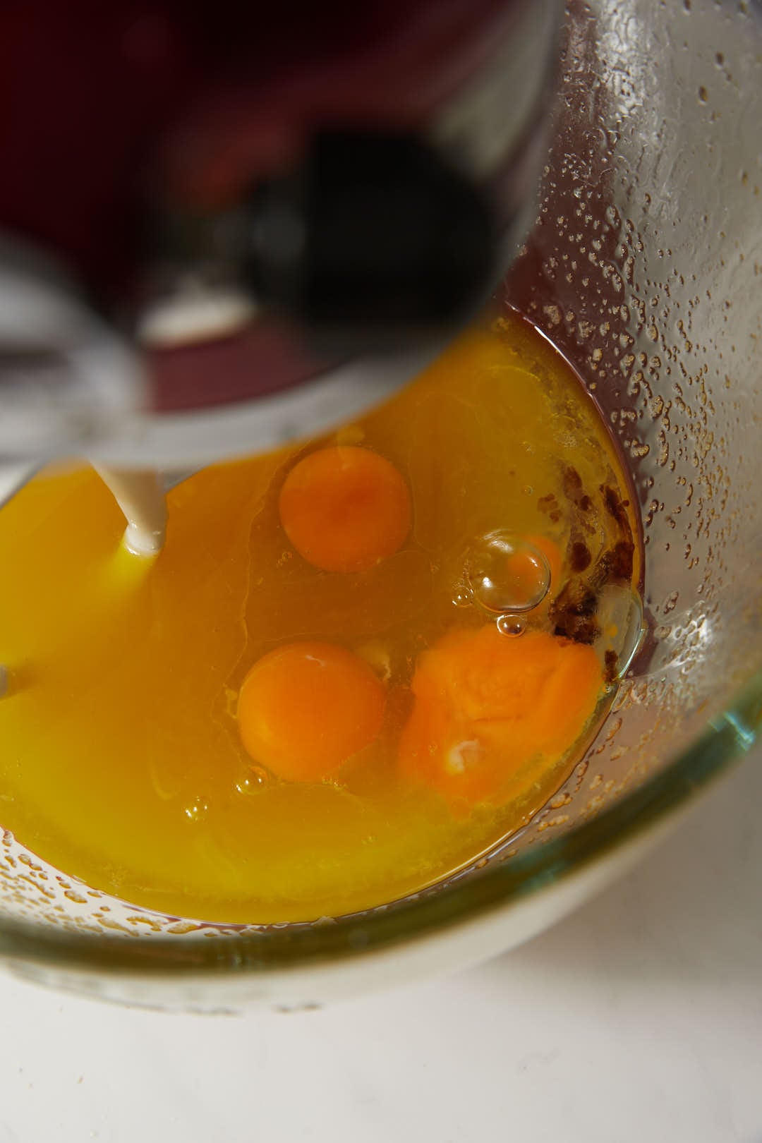 eggs added to a creamed butter and sugar mixture in a glass stand mixer bowl.