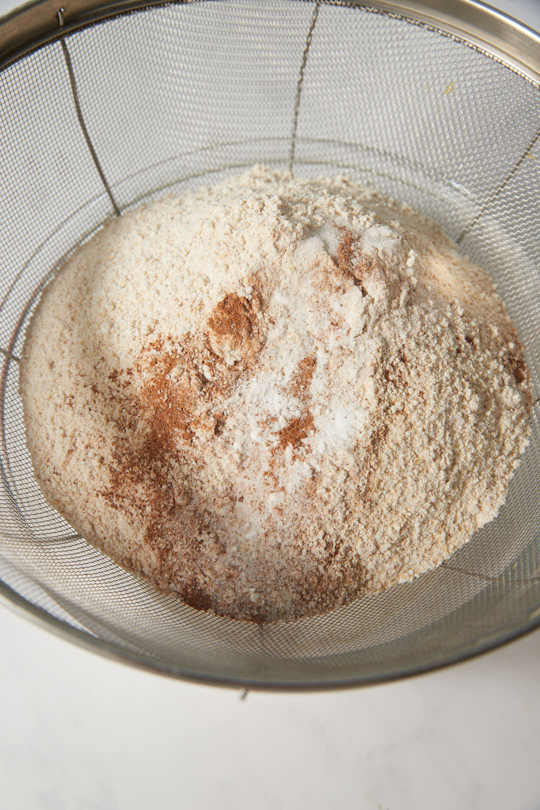 flour in a sifter with cinnamon, cardamom, baking soda and salt.