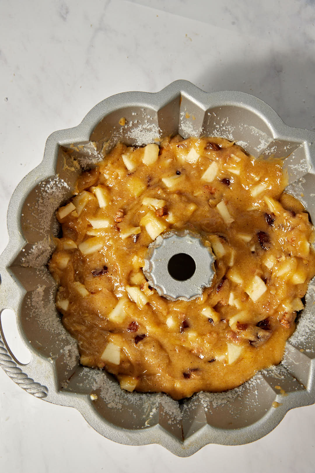 apple date and walnut cake batter in a bundt cake pan before baking.