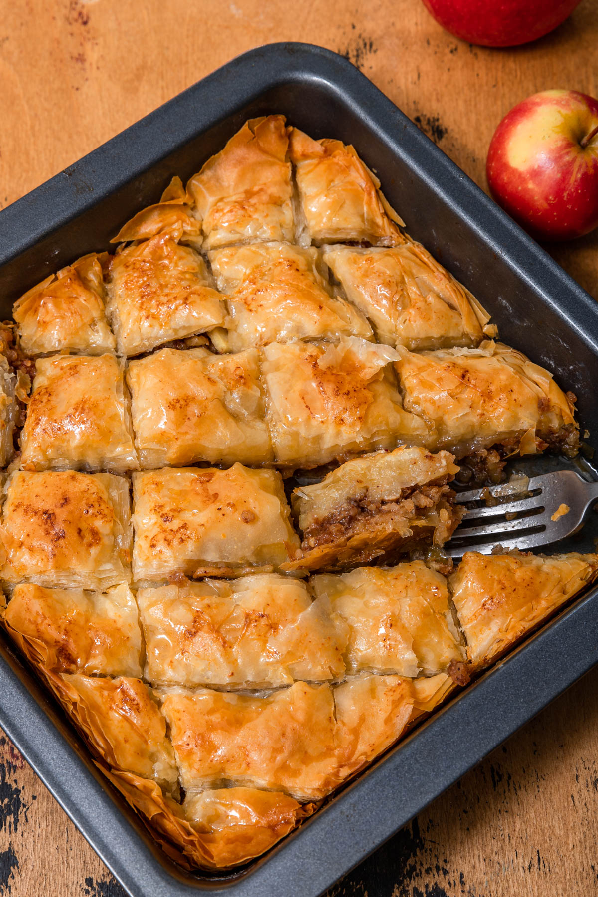 apple baklava in a square pan with a fork removing a piece.