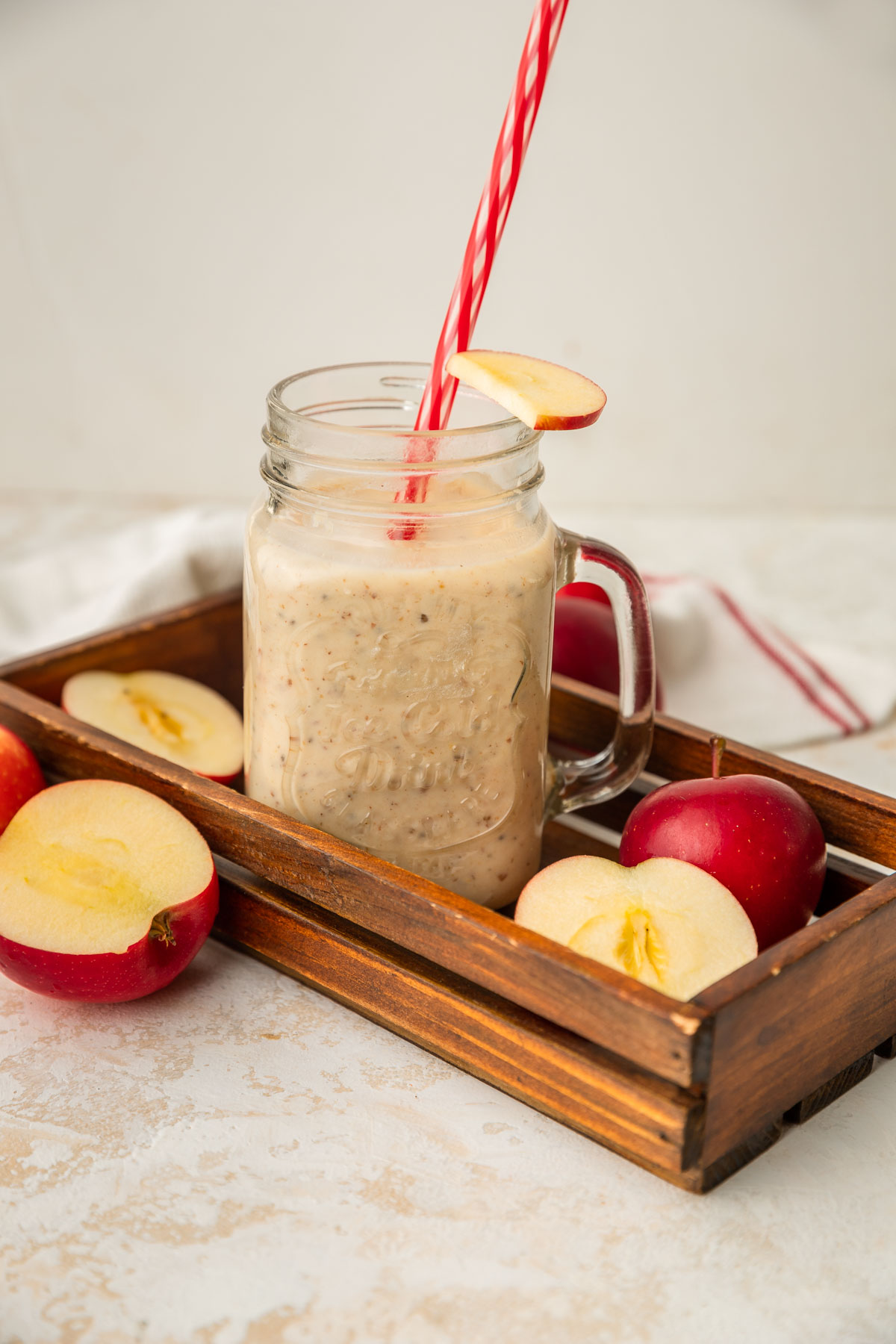Apple date smoothie on wooden tray with cut apples around it.