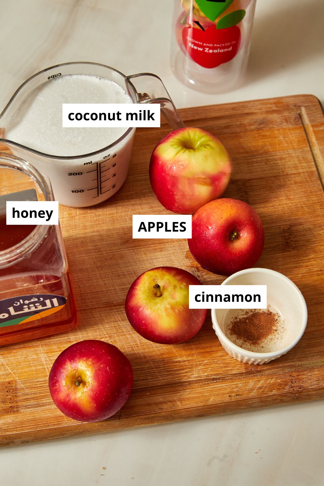 ingredients needed to make apple popsicles on a wooden chopping board.