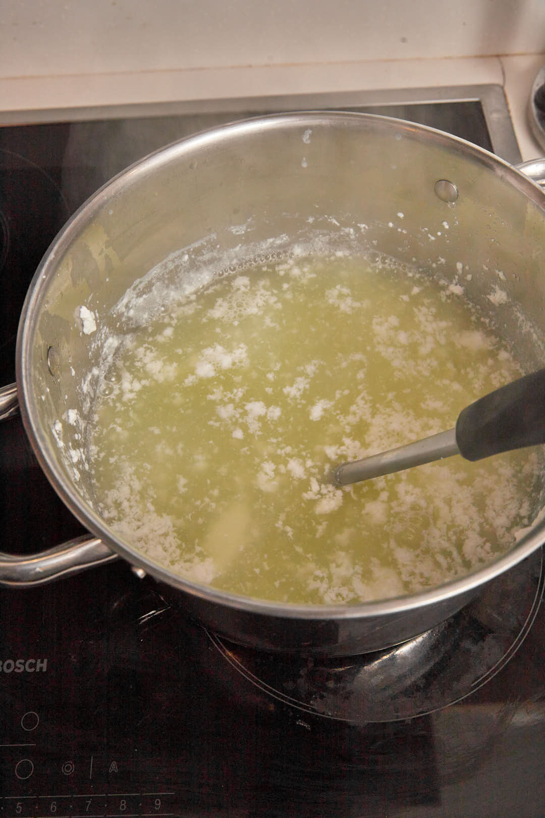 Yellow whey left in a large saucepan after curds have been scooped out.