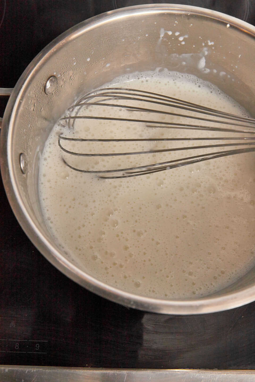milk and cornstarch being whisked into a custard.