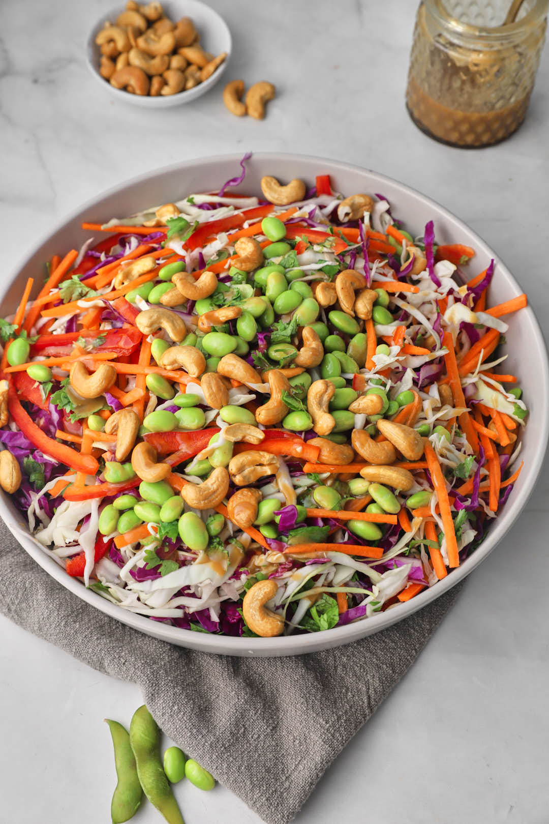 big bowl of chopped asian cashew salad with a jar of dressing in the background.