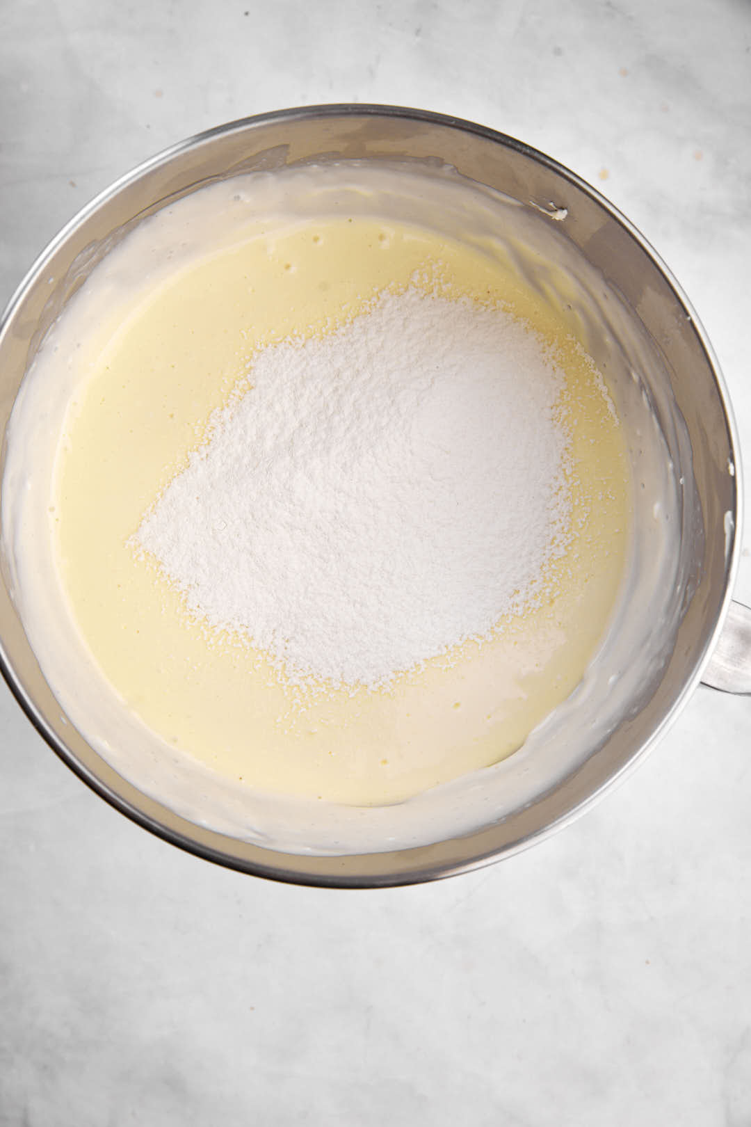 flour added to cheesecake batter in stand mixer bowl.