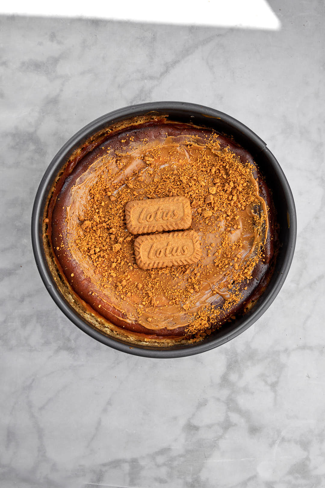 biscoff biscuits and crumbs on cheesecake in springform pan.