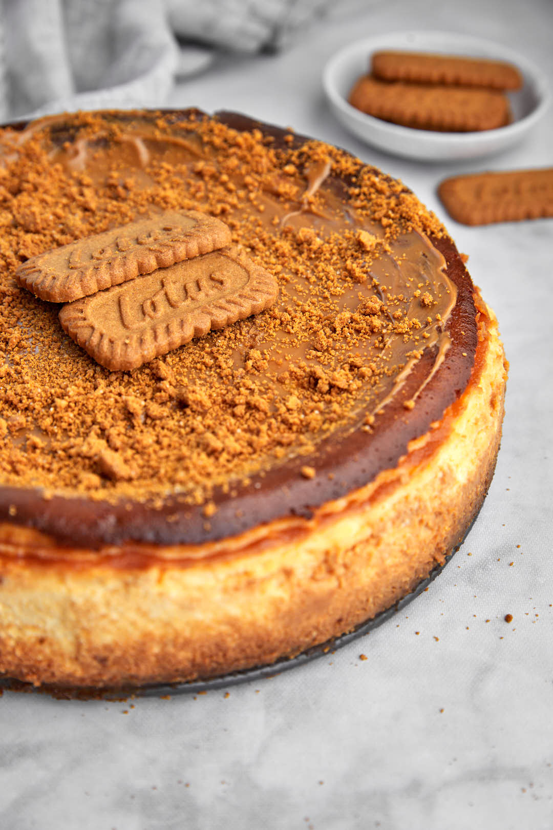 close up photo of baked biscoff cheesecake on white background.
