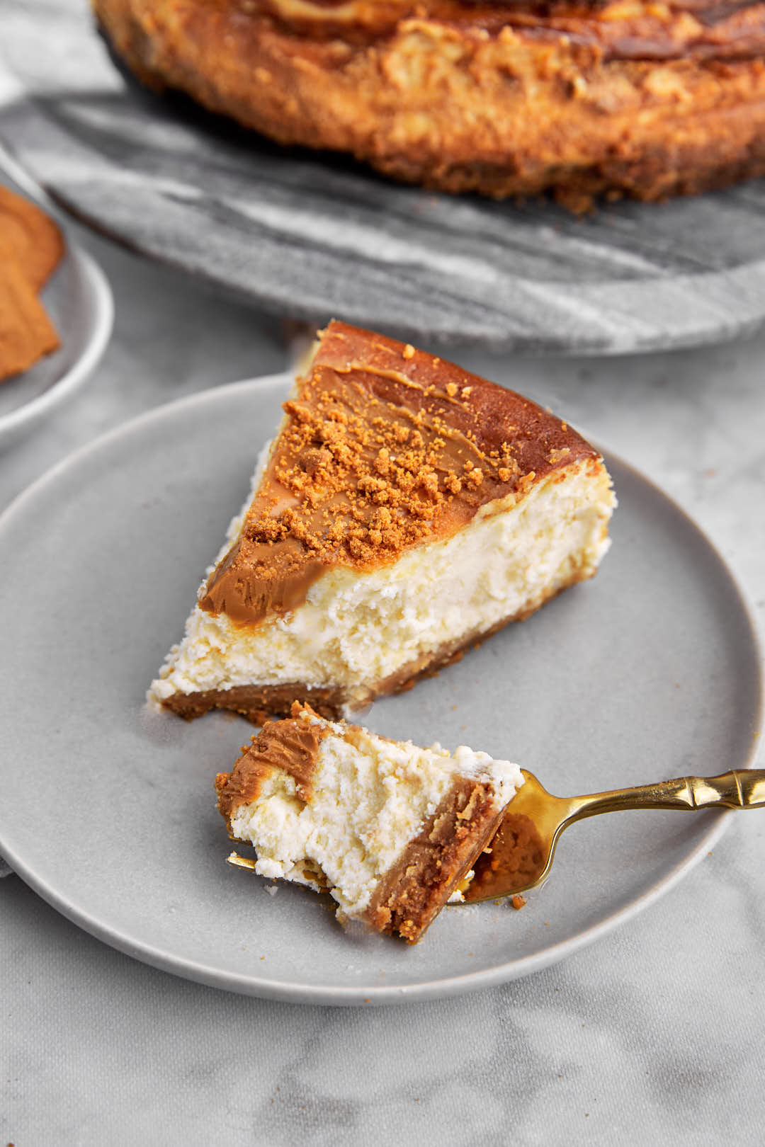 forkful of cheesecake being taken out of a slice on a gray plate.