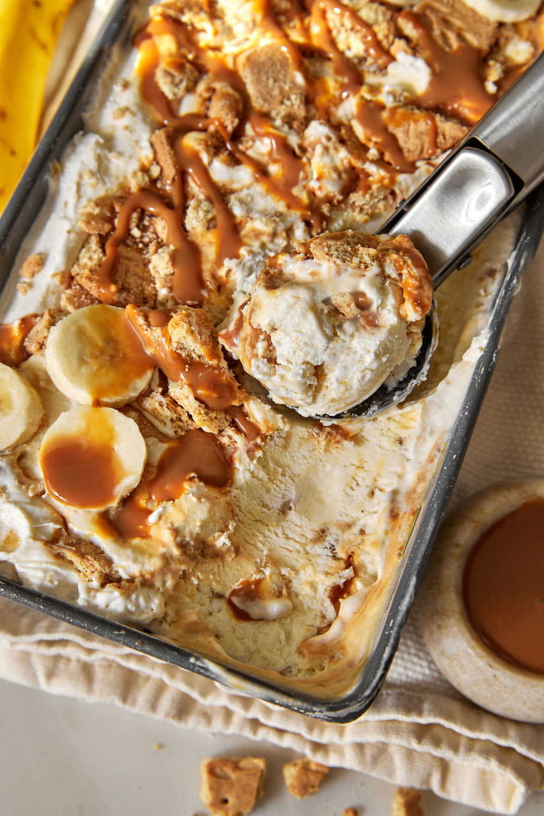 loaf pan full of banoffee ice cream with an ice cream scoop in it.