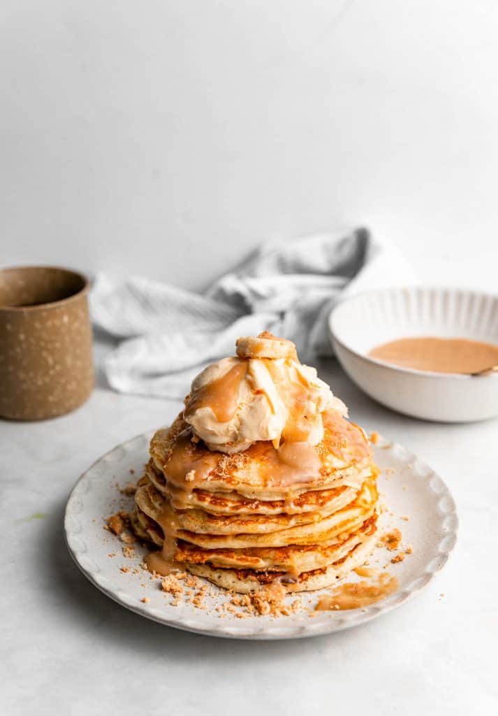 stack of banana toffee pancakes with coffee mug in background