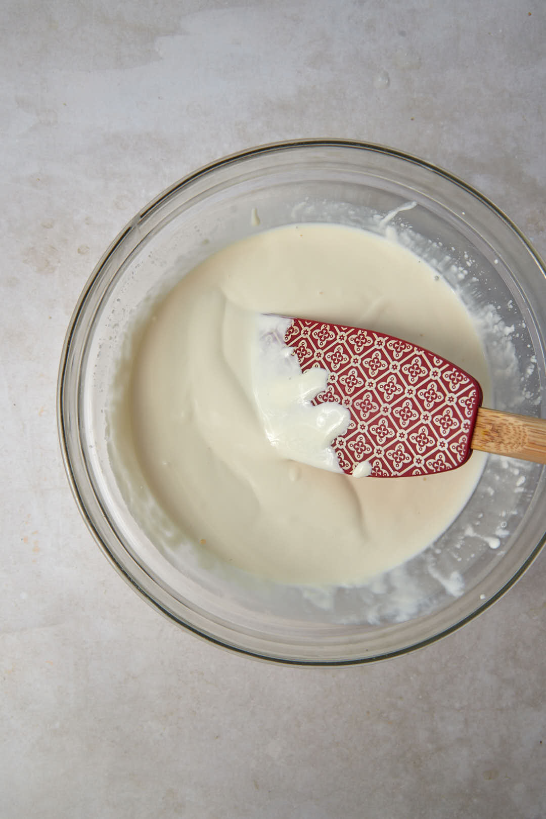 cream in a glass bowl with a red spatula.
