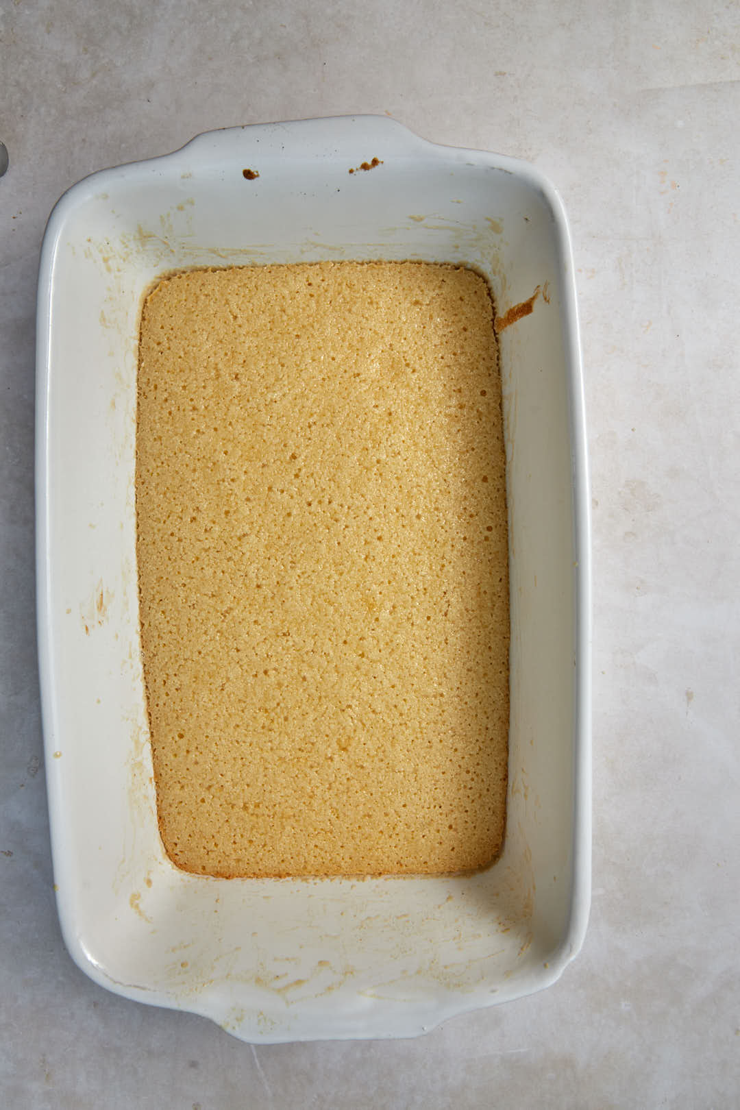 lightly baked basbousa in a white baking pan.